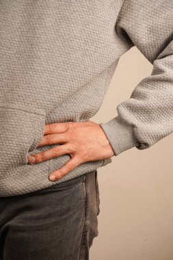 Bir adam elini cebine sokmuş, sıradan bir şekilde kotla dikiliyor. Rahat duruşu kendine güveni taşırken, kıyafetinin basitliği rahatlığı ve rahatlığı vurguluyor.