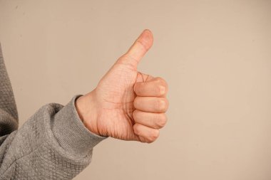 El benzerliği gösteriyor. Sade, parlak bir duvarda, minimalist bir ortamda güven ve uzlaşmayı ifade eden bir başparmak işareti gösterilir.