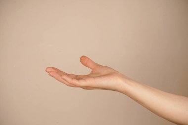 Avuç içinin yukarı dönük olduğu tek bir elin yakın çekimi, hafif bir arkaplana doğru çekiliyor. Jest açıklığı ve kavranabilirliği simgeliyor. Duruşun basitliği, temiz ve minimalist tarzı vurgular.