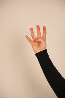 Elin dört numarayı gösteriyor. Avuç içini aç. Avuç içi açık olan el, yardım ya da iletişim anlamına gelir. Basit bir arka plan jestin berraklığını arttırır.