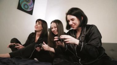 Siyah pijamalı üç kadın ellerinde joysticklerle bir gece dışarı çıkmanın keyfini çıkarıyorlar. Bir dizüstü bilgisayarın etrafında arka planda bir ışık duvarına karşı toplanmışlar.