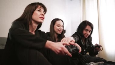 Siyah pijamalı üç kadın ellerinde joysticklerle bir gece dışarı çıkmanın keyfini çıkarıyorlar. Bir dizüstü bilgisayarın etrafında arka planda bir ışık duvarına karşı toplanmışlar.