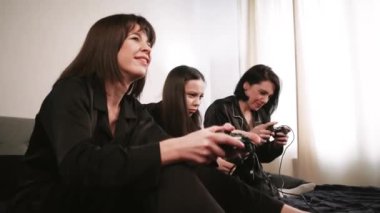 Siyah pijamalı üç kadın ellerinde joysticklerle bir gece dışarı çıkmanın keyfini çıkarıyorlar. Bir dizüstü bilgisayarın etrafında arka planda bir ışık duvarına karşı toplanmışlar.