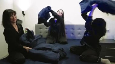 Üç kız pijama partisine hazırlanırken eğleniyorlar. Bekarlığa veda partisinde eğlenceli atmosfer, kadınlar yastık fırlatır.