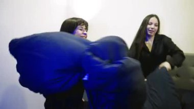 Üç kız pijama partisine hazırlanırken eğleniyorlar. Bekarlığa veda partisinde eğlenceli atmosfer, kadınlar yastık fırlatır.