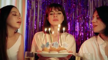 Masanın üzerinde mumların sıkıştığı çörekler var. Doğum günü kutlaması sanki bir doğum günüymüş gibi neşeli bir şekilde gerçekleşiyor.