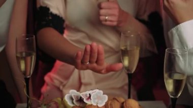 Gelin, arkadaşlarına manikür ve parmağında bir yüzük gösterir. Gelin, düzgün saç kesimi ve kakülleri olan Avrupalı bir kadın.