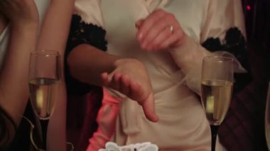 Gelin, arkadaşlarına manikür ve parmağında bir yüzük gösterir. Gelin, düzgün saç kesimi ve kakülleri olan Avrupalı bir kadın.