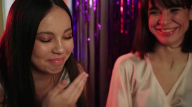 Üç kadın sıcak bir bekarlığa veda partisinin tadını çıkarıyor. Yanında abur cuburlar ve şampanya, birlikte gülüp güzel anlar paylaşıyorlar.