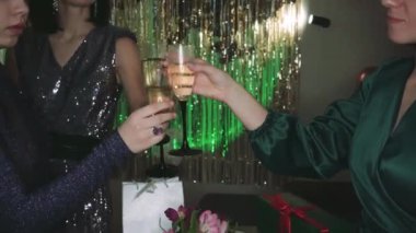 Bir kadın şampanyayla kadeh kaldırıyor yeşil ışıkla aydınlatılmış, arka planda balonlar olan bir odada. Doğum günü veya kutlama temaları için mükemmel