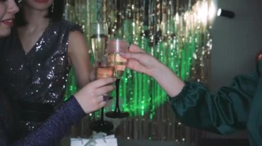 Bir kadın şampanyayla kadeh kaldırıyor yeşil ışıkla aydınlatılmış, arka planda balonlar olan bir odada. Doğum günü veya kutlama temaları için mükemmel