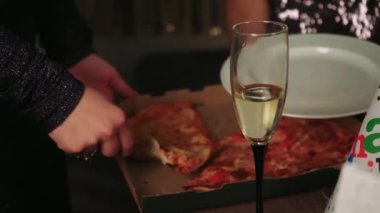 Yakın arkadaşlar pizza ve şekerlemeleri beyaz tabağa koymaya yardım eder. Mutlu bir doğum gününü dekorasyon ve hediyelerle kutlarlar. Arka planda, evde doğum günü için dekor var.