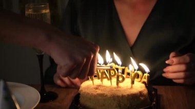 Doğum gününü yanan mumlar, yeşil elbiseler ve mum ışığında kutlayan bir kadın. Doğum günü mumlarını üflerken şampanya ile kutlama yapan bir kadının yakın çekimi.