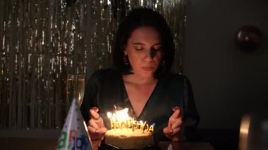 Pullu elbiseli bir kadın doğum günü pastasına mum üflüyor ve kutlamaya sıcaklık katıyor.