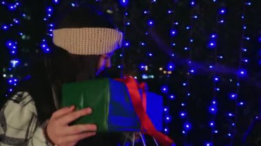 Sıcak kışlık elbiseli kadınlar gece şehrinde mavi ışıklarla çevrili hediyelerini değiş tokuş ederler. Arkadaşlıkları ve tatil buluşmalarını kutlamak için mükemmel.