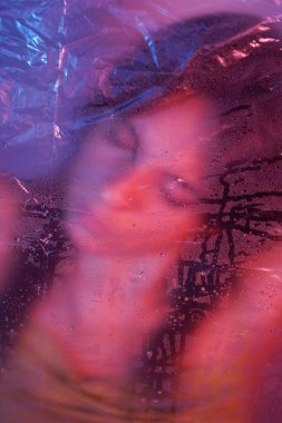 Plastiğin pürüzsüz yüzeyine bastırırken neon yansımaları dalgalanır.