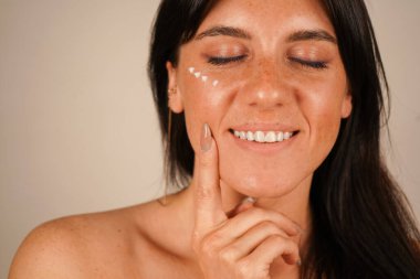 She spreads moisturizer over her face with her fingertips, emphasizing hydration and nourishment clipart