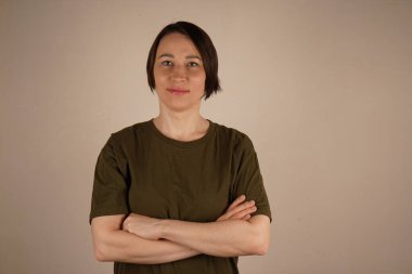 Kısa saçlı ve kahverengi gözlü esmer bir kız. O, kollarını önünde kavuşturdu. Yakın plan fotoğraf.