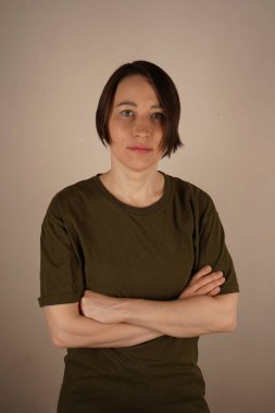 Kız başını kaldırdı. Kısa saçlı ve kahverengi gözlü esmer bir kız. Kollarını önünde kavuşturmuş ve doğrudan kameraya bakıyor.