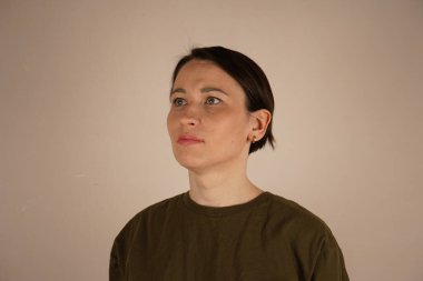 Asyalı görünümlü bir kadın saçlarını geri almış ve gri gözleriyle yan tarafa bakıyor.