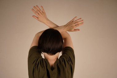 Gri arka planda gözlerini kapatan korkmuş bir kadının görüntüsü. Kafasının arkası tamamen çevrilmiş.