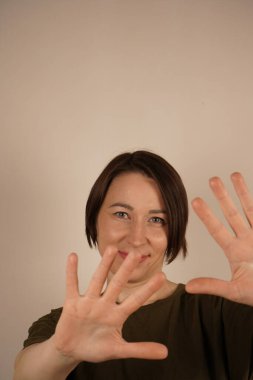 Oldukça çekici bir kadının portresi oldukça pozitiftir. Merhaba, selamlar. Gri bir arkaplanda izole edilmiş