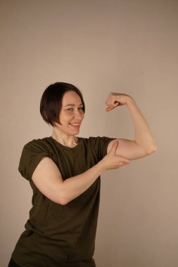 Olgun, güçlü, neşeli kadın. Evdeki spor kaslarının pastel grisi stüdyo arka planında izole olduğunu gösteriyor. İyi ruh hali kavramı