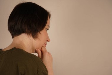 Kafasının arkasında duran esmer bir kadının fotoğrafı çekiliyor. Hafifçe döndü ve yana baktı. Yüzü yakın planda çekilmiş.