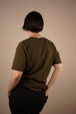 Gri duvarın karşısındaki bayan ellerini ön cebine koydu. Ama o geri döndü. Kapat.