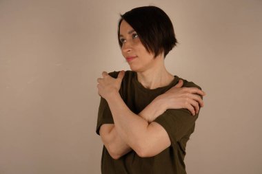 Sakin bir kadın iki koluyla kendine sarılmayı hayal eder, gözlerini kapalı tutar ve yan tarafa bakar, rahat hisseder, rahat kıyafetler giyer. Kapat.