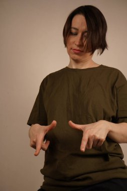 Kısa saçlı bir esmer neredeyse alttan tam yükseklikte. İşaret parmaklarını yere doğrultuyor. Kapat.