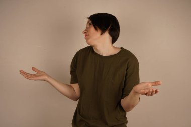 İnce saçlı mutlu genç kız ellerini açık bej arka planda izole edilmiş sürpriz bir jest ile açıyor.