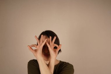 Gri izole bir arka planda her şeyin yolunda olduğunu gösteren gülümsemeli bir kız.