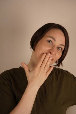 Yeşil elbiseli neşeli olgun bir kadının yüzünün yanında el ele tutuşması ve gri arka planda mutlu bir gülümseme. Başarı ve zaferin tadını çıkarıyor. İndirim ve satış. Reklam kavramı