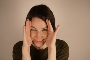 Neşeli, mutlu, esmer bayanın yakın bir fotoğrafı. Gri saçlarıyla geniş bir Hollywood gülümsemesi sergiliyor.