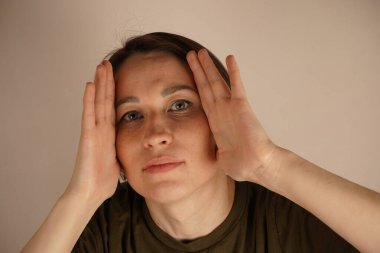 Şok olmuş genç bir kızın fotoğrafı. Şaşırmış eller, yanaklara dokunuyor. Renk arkaplanı üzerinden izole haberler veriliyor.