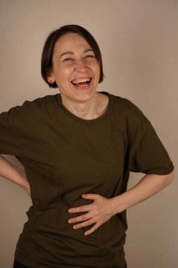 Young brunette woman standing over background smiling and laughing hard out loud because funny crazy joke with hands on body. Close up clipart