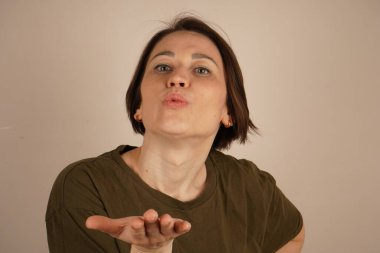 Bej arka planda hava öpücüğü veren neşeli güzel bir kadın görüntüsü