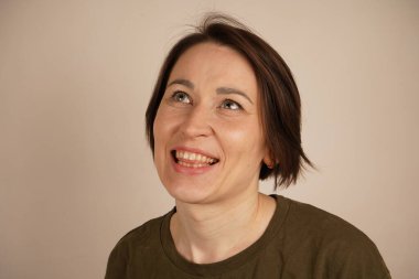 Gri arka planda duran komik çekici kadın. Şakayla göz kırpıyor, kameraya dilini gösteriyor.