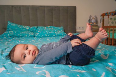 Ayaklarını gökyüzüne doğru uzatıyorlar, siyah pantolonlu çocuk ve gri bluzu yavaşça gülümsüyor, mavi zeminde sırtüstü yatıyorlar.