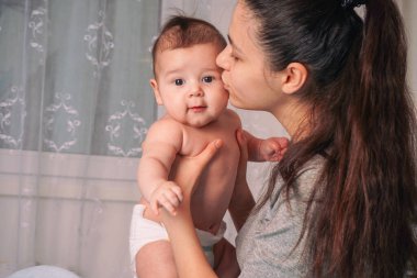 Oda, başucu lambasıyla sıcak bir şekilde aydınlatılıyor. Mavi yatak örtüsüne yumuşak, davetkar bir ışık yansıtıyor. Anne ve çocuğun yüzlerindeki hassas ifadeler...