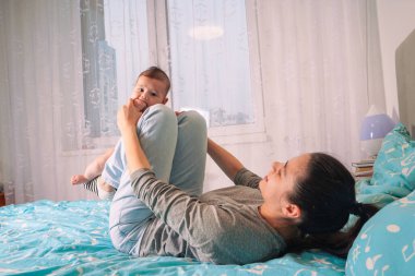 Annesinin kucağında çırılçıplak iki aylık bir çocuğun yakın çekimi. Çok yakından ilgilenen bir anne var.