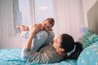 Beyaz bezli küçük bir çocuk annesinin kucağında yatıyor. Bir bebeğin güzel bir portresi. Yakın çekim.