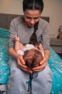 Anne kucağında ağlayan yeni bebeğini kucağında, nazikçe bebeğin başını tutuyor.