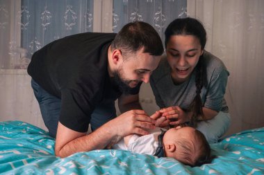 Bebek battaniyenin üzerinde yatarken huzurlu bir an, ebeveynlerinin dikkatli bakışları altında güvende.