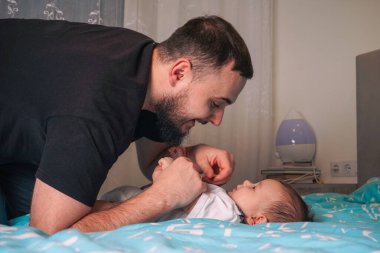 Yeni doğmuş bebeğini kucağında tutan genç babanın portresi. Babalık sevgisi Bekar Babalar Günü konsepti