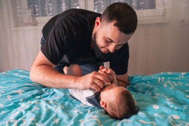 Babalar, sevgi ve güven dolu sessiz bir anı paylaşırken nazikçe bebeğin yanında dinlenirler.