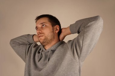 Spor giyimli bir adam ellerini boynuna dolamış. Bu poz bir rahatlama ve dinlenme anını gösteriyor. Dirsekler yanlara doğru açılır.