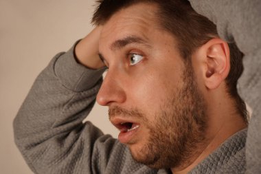 İki eli de başının üstüne oturtulmuşken, adam stres ya da baş ağrısı belirtileri gösteriyor. Duruşu ve ifadesi gerginliği gösteriyor. Bu çekim zihinsel rahatsızlığın fiziksel belirtilerini vurgular.