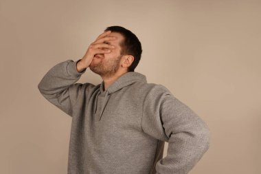 Adam avuç içini yüzüne koyar ve facepalm hareketi yapar. Bu klasik jest hayal kırıklığını, güvensizliği ya da utancı ifade eder. Evrensel bir kızgınlık ya da pişmanlık işaretidir.